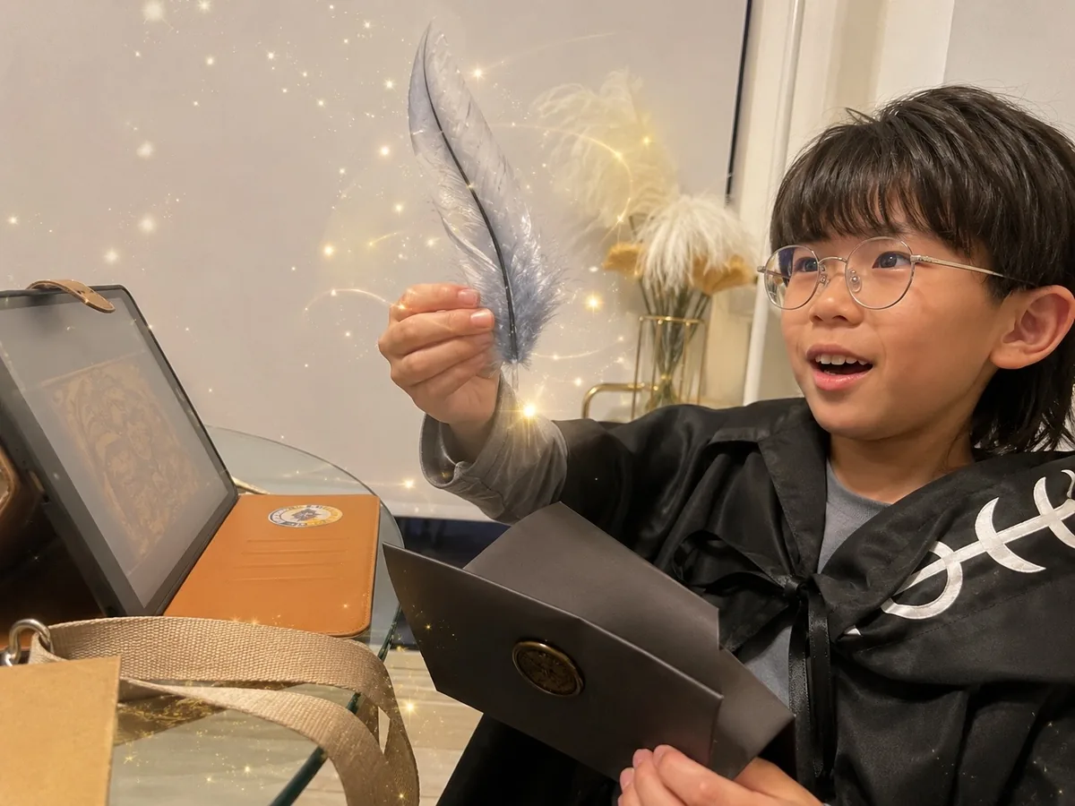 魔法のマントを着て、妖精の羽根と入学許可証に目を輝かせる子ども